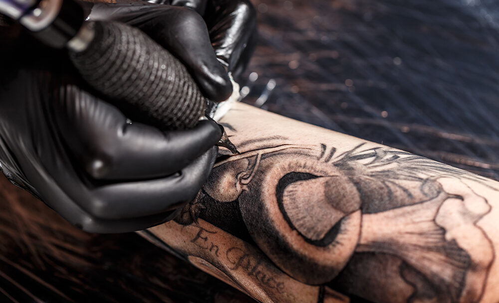 Master tattoo artist in gloves makes tattoo on hand men